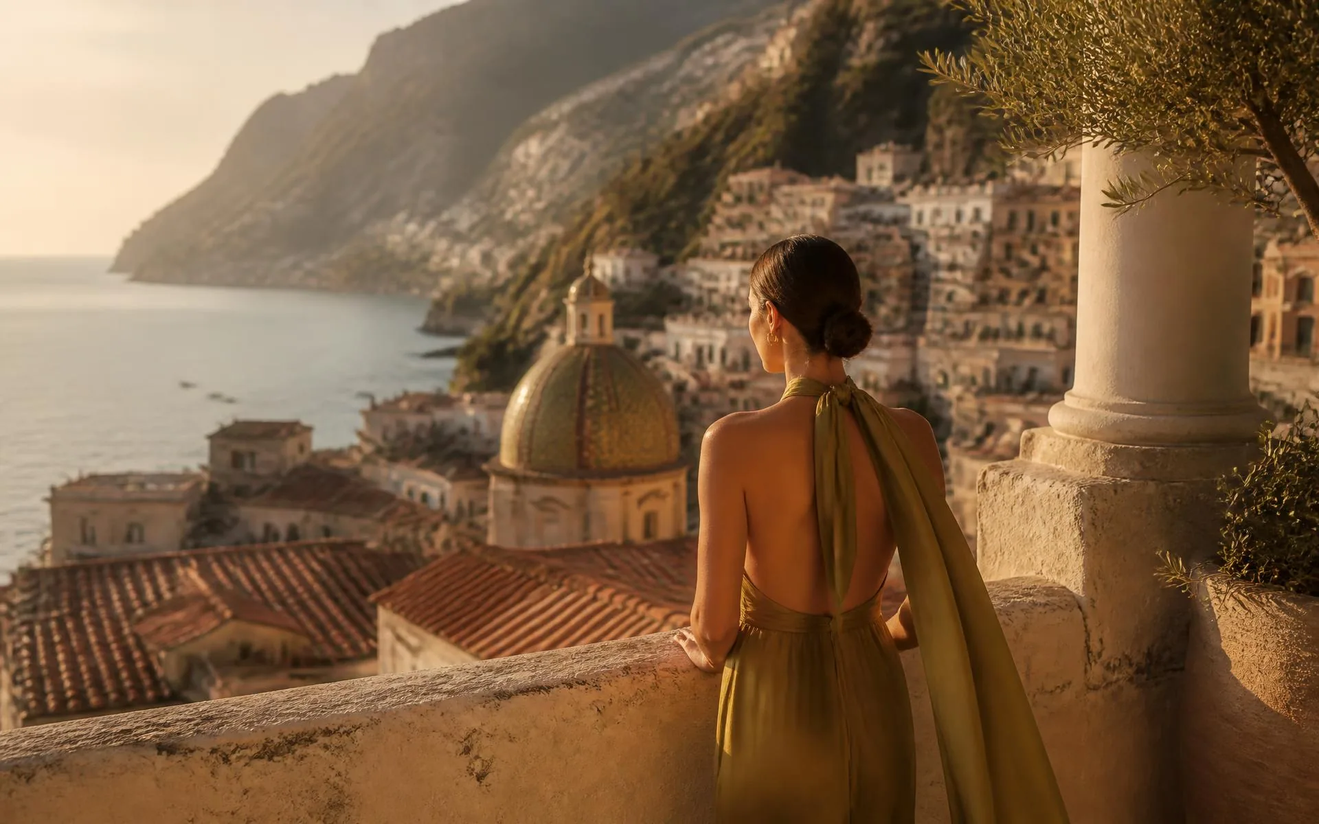 A traveler looking out over a sunlit coastal town and the sea